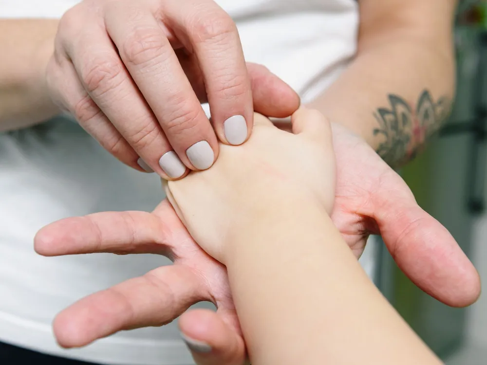 Primo piano di due mani che lavorano lentamente sul palmo della mano di un'altra persona.